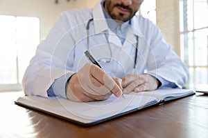 Close up of male doctor writing in medical journal