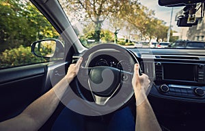 Close up male driver hands on the steering wheel, driver car on the city street