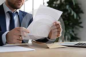 Close up of male employer read paper letter in office