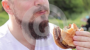 Close-up male face eating a big burger. Hungry young man