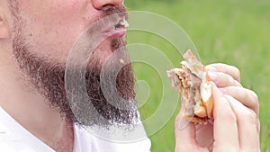 Close-up male face eating a big burger. Snack in nature