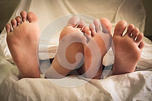 Close up of male and female feet on a bed and couple having sex