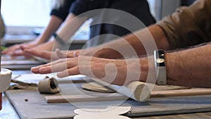 A close-up of a male and female hands potter rolls a clay rolling pin