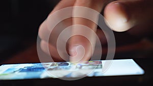 Close up of male finger sliding on touchscreen. Unrecognizable man surfing in internet or social net using his