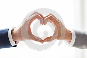 Close up of male gay couple hands showing heart