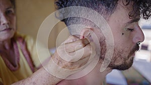 Close up of male getting ear pinched at Thai massage session at the spa