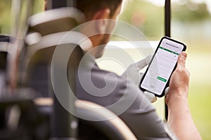 Close Up Of Male Golfer In Buggy Checking Score On Mobile Phone App