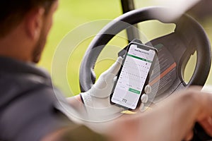 Close Up Of Male Golfer In Buggy Checking Score On Mobile Phone App