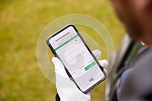 Close Up Of Male Golfer In Buggy Checking Score On Mobile Phone App