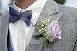 Close-up of male groomsman attire with pink rose corsage photo
