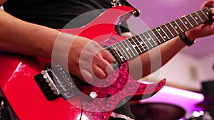 Close-up of male guitarist hands playing on red electric guitar