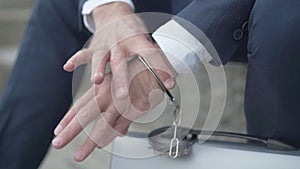 Close-up of male hand chained to attache case with handcuffs. Unrecognizable secret agent with governmental secrecy