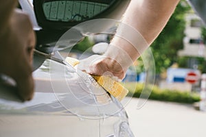 Close up of male hand cleaning car with sponge.