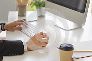 Close-up of male hand clicking wireless digital mouse working with desktop computer at office desk