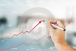 Close up of male hand drawing growing red business chart arrow on blurry office interior background. Finance, profit and increase