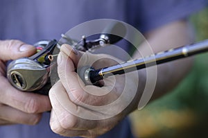 Close-up of a male hand with a fishing rod and a baitcasting reel photo