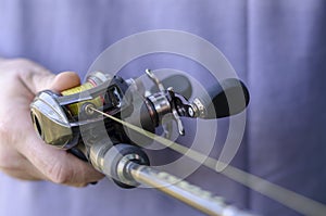 Close-up of male hand with a fishing rod and  baitcasting reel photo