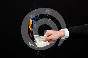 Close up of male hand holding burning dollar money