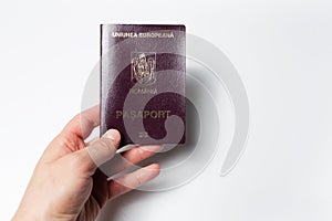 Close-up of male hand holding Romanian passport in hand on white background.