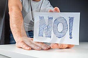 Close-up male hand holds a white card with the word no. Failure disagreement protest