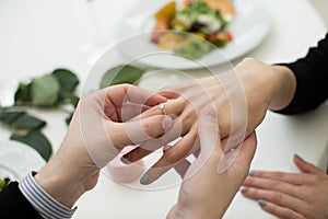 Close Up Of Male Hand Inserting An Engagement Ring Into A Finger.