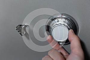 Close-up of male hand, introduces combination security code of safe lock.