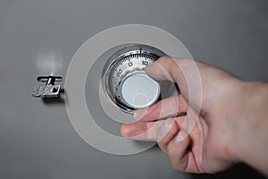 Close-up of male hand, introduces combination security code of safe lock.