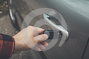 Close up of a male hand opening car door. Person inserts the remote control key in the lock hole of a vehicle. Opening