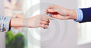 Close up of male hand passing key to female indoors in new apartament. Man handing