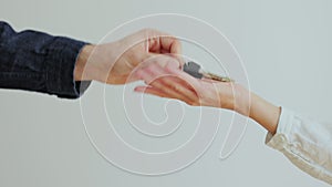 Close up of male hand passing key to female in new apartament. Man handing keys of new house to woman customer. Selling