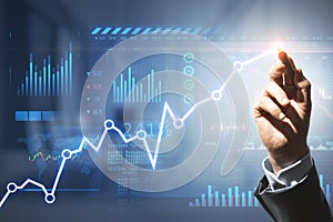 Close up of male hand with pen drawing business chart and map on blurry office interior background. Financial forecast and trade