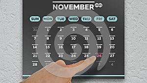 Close-up of a male hand pointing finger to the Black Friday date on the November page of a wall calendar 2021