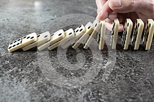 Close-up of male hand preventing line of domino tiles from toppling and falling