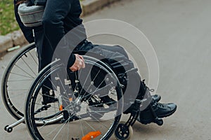 Close-up of male hand on wheel of wheelchair during walk in park