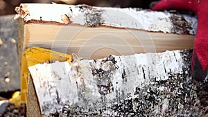 Close up of male hands chopping birch firewood on a hydraulic wood splitter. Sawmill. Birch firewood for fireplac