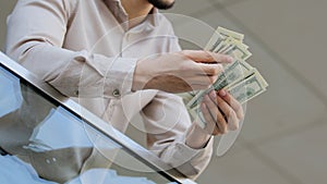 Close-up of male hands counting dollar bills outdoors. Business man holding count money cash in office. Money