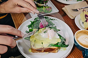 Close-up of male hands cutting with knife delicious toast with poached egg