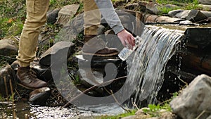 close-up male hands draw water from a mountain river. man drinking water
