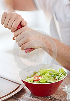 Close up of male hands flavouring salad in a bowl