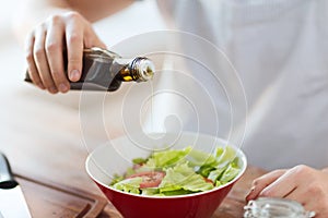 Close up of male hands flavouring salad in a bowl