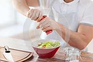 Close up of male hands flavouring salad in a bowl