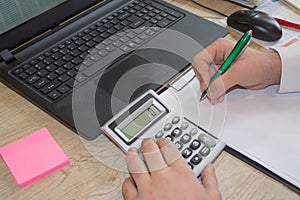 Close up of male hands on her calculator`s keyboard. The second hand in on the touchpad. Concept of accountant`s work