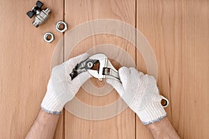 Close-up of male hands holding the ball valve and a wrench.