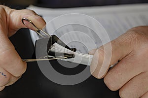 Close-up of male hands holding paper sheets with black metal clip