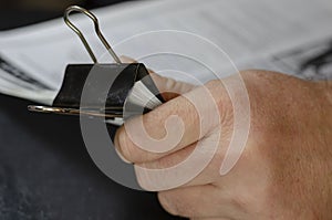 Close-up of male hands holding paper sheets with black metal clip