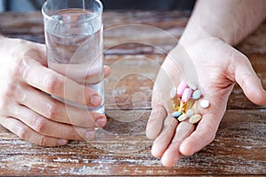 Close up of male hands holding pills and water