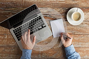 Close up of male hands with laptop and notebook