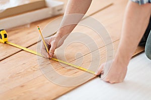 Close up of male hands measuring wood flooring