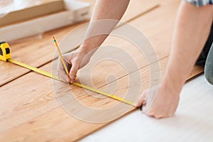 Close up of male hands measuring wood flooring photo