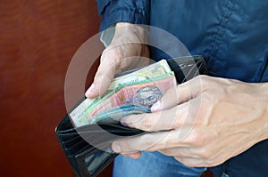 Close up male hands opened the wallet or purse with ukrainian money currency hryvnia